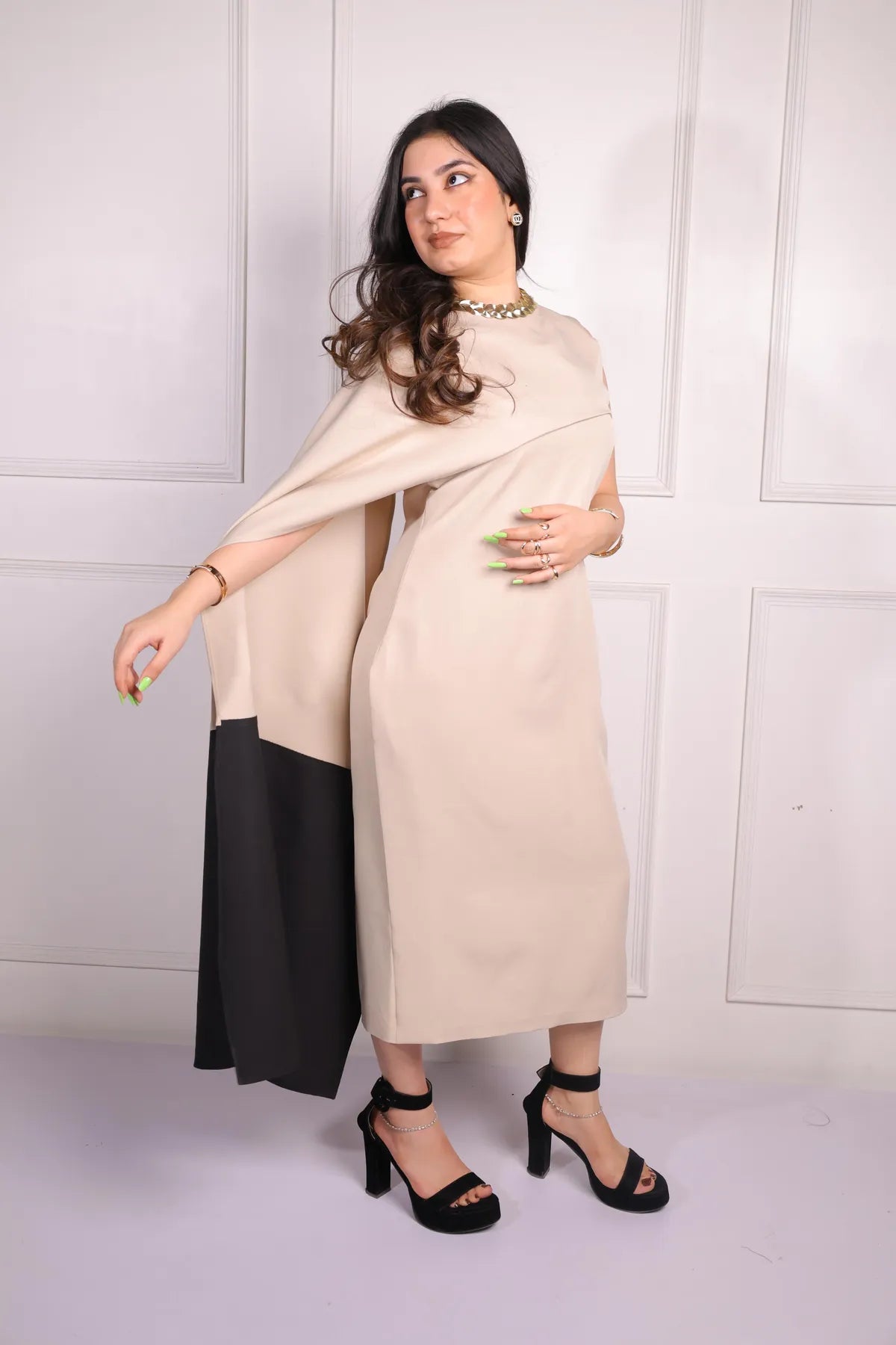 Woman wearing a beige dress with black accents against a white background