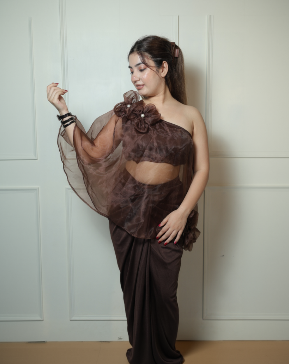 Woman wearing a brown floral dress against a white wall