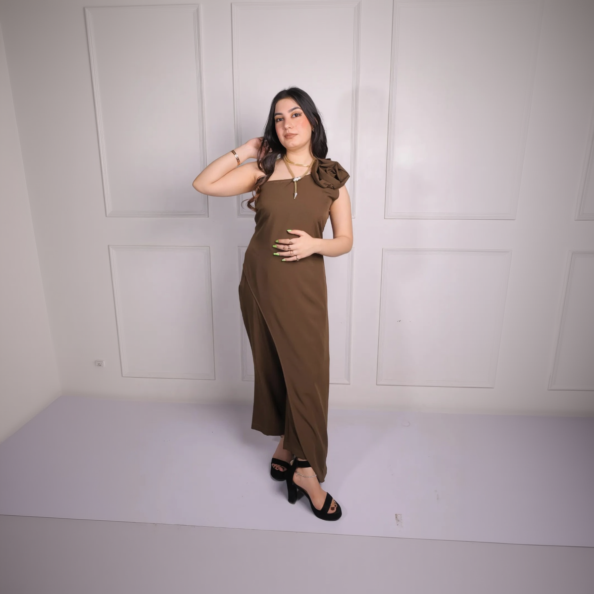 Woman wearing a brown dress against a white wall