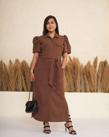 Woman in a brown dress standing in front of a field of wheat.