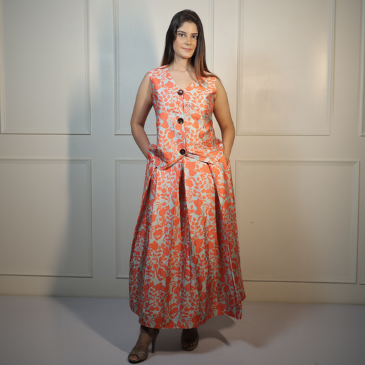 Woman wearing an orange floral dress with black buttons against a white wall.