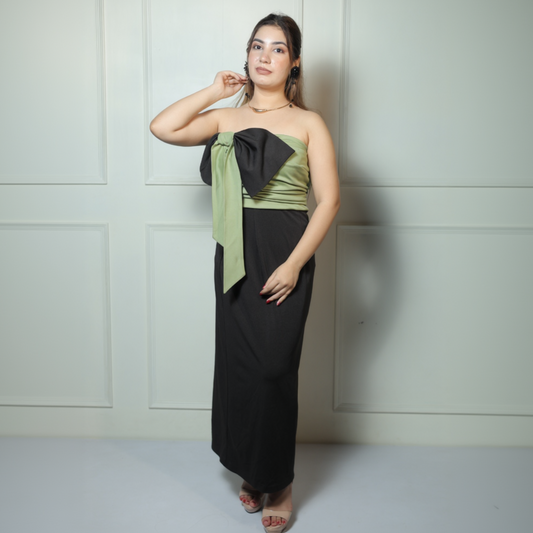 Woman wearing a black and green strapless dress against a light gray wall.