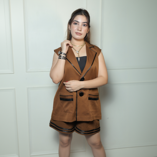 Woman wearing a brown vest and shorts set against a white wall.
